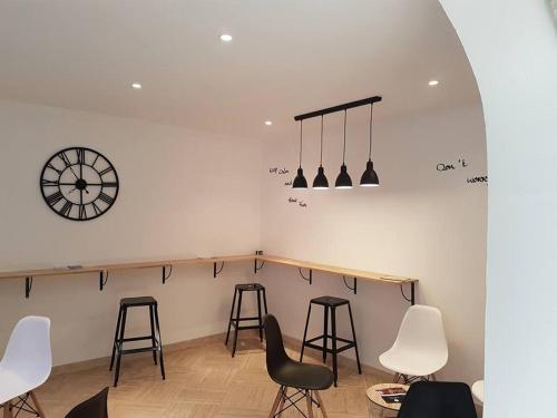 a room with stools and a clock on the wall at Hôtel Le Sainte Florence in Sainte-Florence