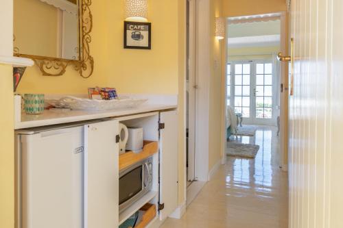 a kitchen with yellow walls and a counter with a microwave at Haus am Strand - on the Beach in Wilderness