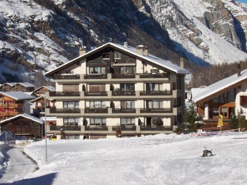 a large building in the snow in front of a mountain at Modern Täsch Apartment with Free Parking in Täsch