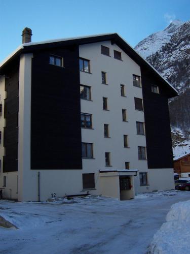 a large building with snow in front of a mountain at Modern Täsch Apartment with Free Parking in Täsch