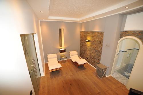 uma sala de estar com duas cadeiras brancas e uma parede de tijolos em Hotel Rheinischer Hof em Erkelenz