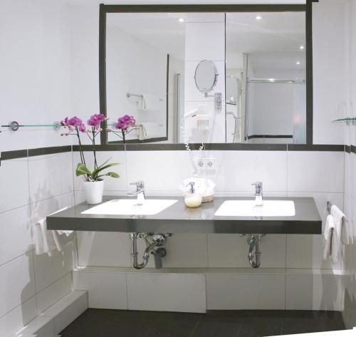 a bathroom with two sinks and a large mirror at Strandhotel Löchnerhaus in Reichenau