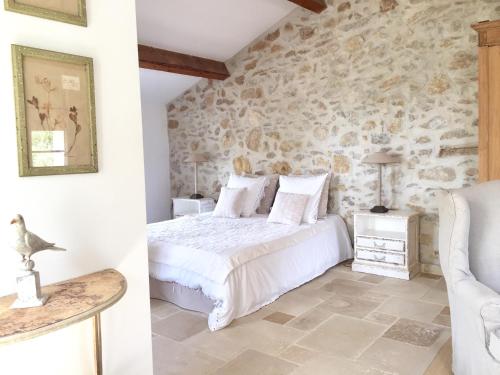 Bastide de Fontvieille في سان سير سور مير: غرفة نوم بسرير وجدار حجري