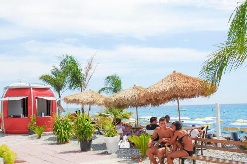 un gruppo di persone sedute sulla spiaggia di Afrodite Boutique Hotel a Bovalino Marina