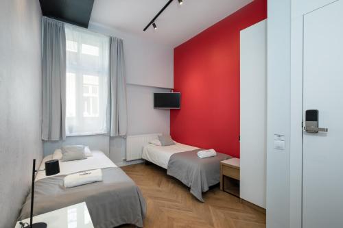 2 camas en una habitación con una pared roja en Rainbow Apartments 3, en Cracovia