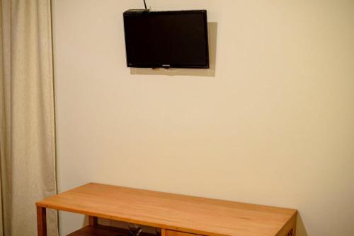 a flat screen tv on a white wall with a wooden table at Hotel Vento Brasil in Paracuru
