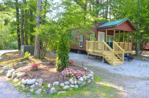 a cabin in the woods with a porch and flowers at Lake George Escape in Warrensburg