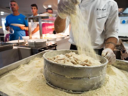 a chef mixing food in a pot in a kitchen at Saracen Sands Hotel & Congress Centre - Palermo in Isola delle Femmine