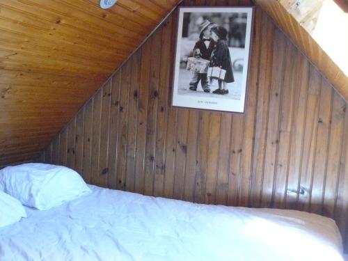 - une chambre dotée d'un mur en bois avec un lit et une photo dans l'établissement SAUVAGERE - Studio balcon, Plage 300m - UD67, à Carnac