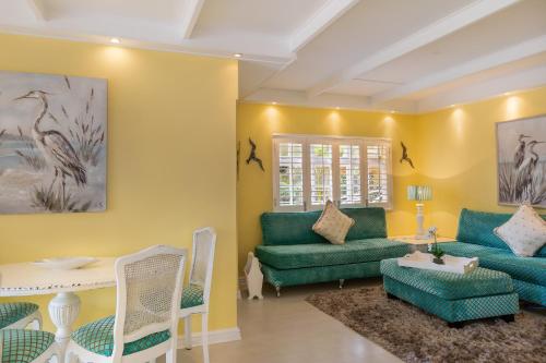 a living room with green furniture and yellow walls at Haus am Strand - on the Beach in Wilderness