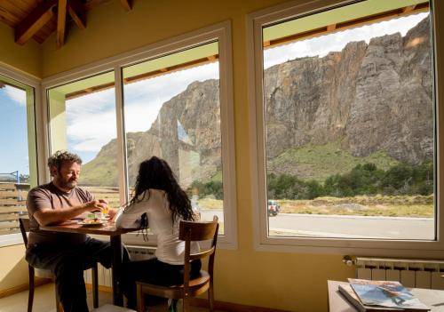 a man and woman sitting at a table looking out of a window at Hostería Vertical Lodge in El Chalten