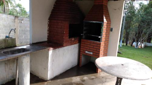 um forno de tijolo exterior com um lavatório e uma mesa em Chácara Temporada Locação em Ibiúna em Ibiúna