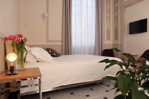 a bedroom with a bed and a table with a vase of flowers at Hotel Le Nuvole Residenza d'Epoca in Genoa