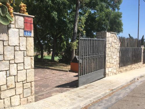 a gate on the side of a stone fence at Villa Entrenaranjos in Picassent