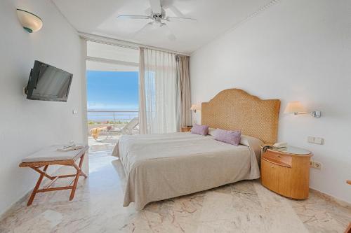 a bedroom with a bed and a tv and a window at Anfi del Mar 2 in La Playa de Arguineguín