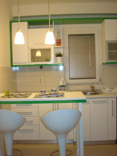 a kitchen with two white stools and a counter top at Apartments Nela in Ohrid