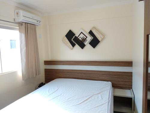 a bedroom with a white bed and some pictures on the wall at Lacqua diRoma 1 - Apartamentos JN in Caldas Novas