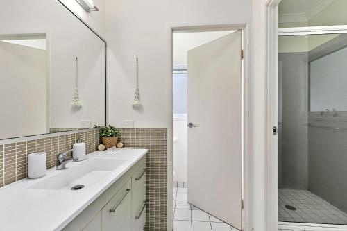 a white bathroom with a sink and a shower at Grevillea in Point Lookout