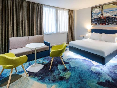 een hotelkamer met een bed en een tafel en stoelen bij ibis Styles London Heathrow Airport in Hillingdon