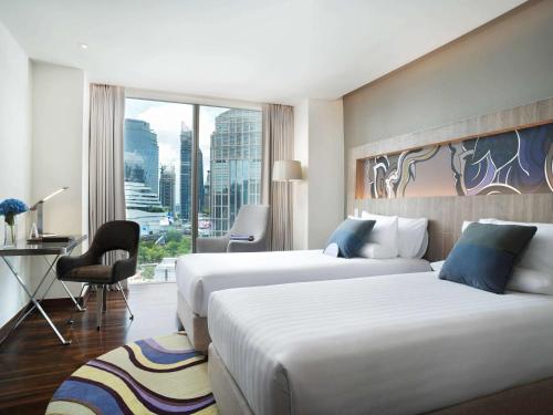 Novotel Bangkok Sukhumvit 20 في بانكوك: غرفة فندقية بسريرين ومكتب