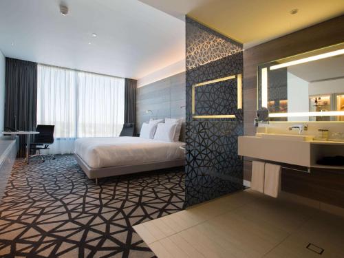 a hotel room with a bed and a sink at Pullman Sydney Airport in Sydney
