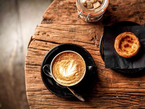 a cup of coffee and a pastry on a wooden table at ibis Cambridge Central Station in Cambridge