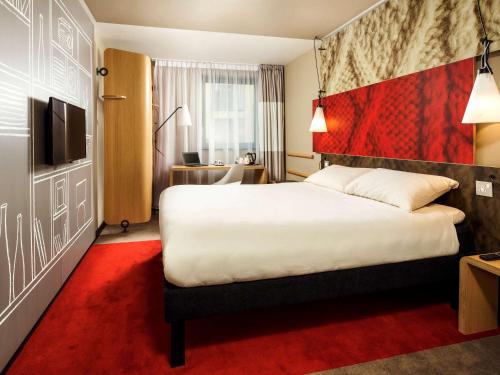 a hotel room with a bed and a red carpet at ibis Cambridge Central Station in Cambridge