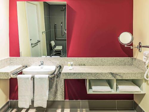 a bathroom with a sink and a red wall at Mercure Ribeirao Preto in Ribeirão Preto