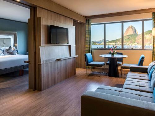 a hotel room with a couch and a bed and a table at Novotel RJ Praia de Botafogo in Rio de Janeiro