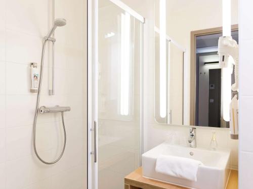 
a bathroom with a shower, sink, and mirror at ibis De Haan in De Haan
