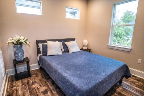 a bedroom with a blue bed with two windows at Beautiful Guest House on New Built Home Near Downtown in San Antonio