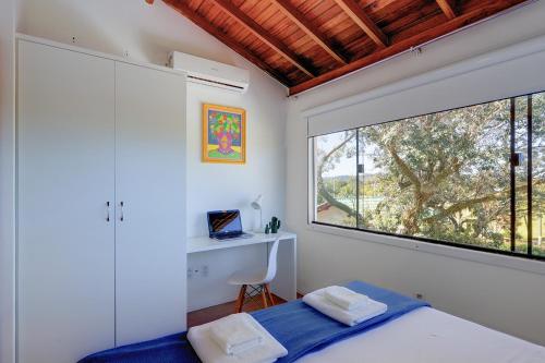1 dormitorio con cama y ventana grande en Loft na Lagoa da Conceição, en Florianópolis