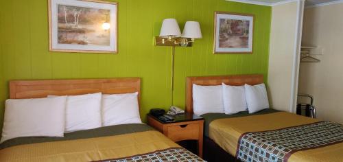 a hotel room with two beds and green walls at Pinebrook Motel in Lake George