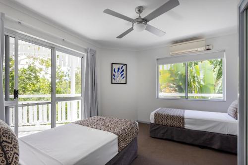 um quarto com 2 camas e uma ventoinha de tecto em The White House Port Douglas em Port Douglas
