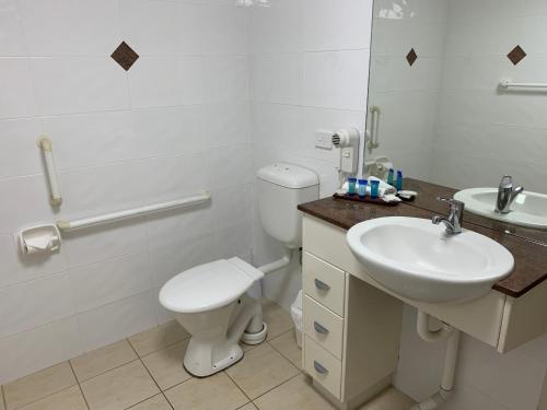 a white bathroom with a toilet and a sink at Northpoint Apartments in Port Macquarie