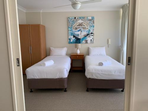 a room with two beds and a painting on the wall at Northpoint Apartments in Port Macquarie