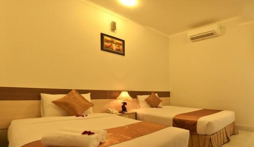 Una habitación de hotel con dos camas y una lámpara. en Hau Giang 2 Hotel Cần Thơ, en Can Tho