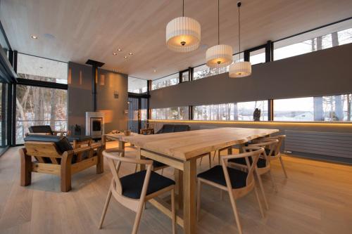 a dining room with a large wooden table and chairs at Hiyoku 飛翼 in Niseko