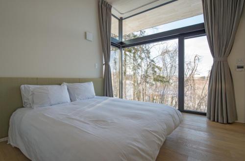 a bedroom with a large bed and a large window at Hiyoku in Niseko