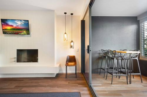 a living room with a table and chairs and a tv at Luxury Spa Retreat with Ocean and Hinterland Views in Montville