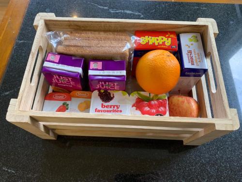 een houten bak gevuld met voedsel en een sinaasappel bij U Studios Masterton in Masterton