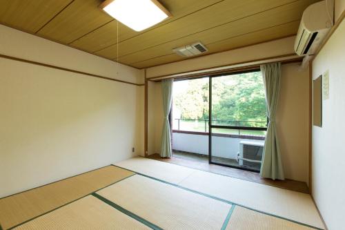 een lege kamer met een groot raam en uitzicht bij Showa Forest Village in Chiba