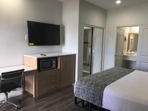 a hotel room with a bed and a desk with a tv at Cali Inn in Carson