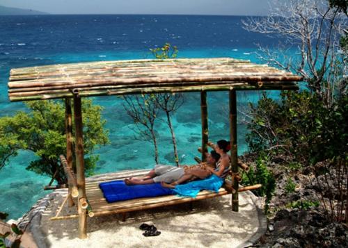 a group of people sitting on a swing over the ocean at Bluewater Sumilon Island Resort in Sumilon Island
