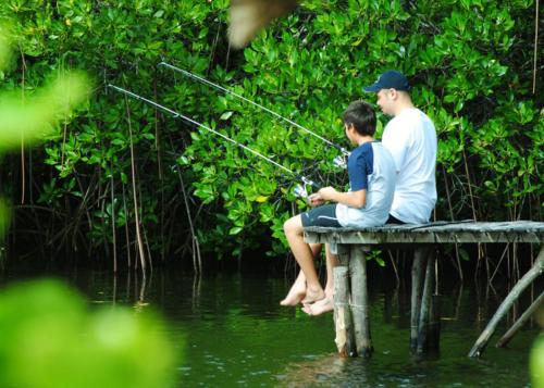 a man and a boy sitting on a pier fishing at Bluewater Sumilon Island Resort in Sumilon Island