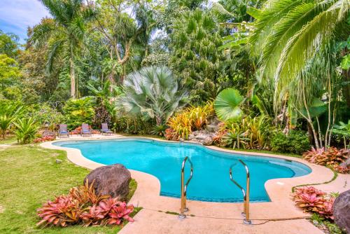 a swimming pool in a garden with palm trees at Shawandha Lodge in Puerto Viejo