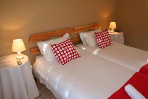 two beds with red and white pillows in a bedroom at Karoopark Guest House in Graaff-Reinet