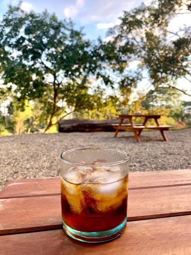 a glass of drink sitting on a wooden table at Bosque de Aventura & Glamping El Faro in La Mesa
