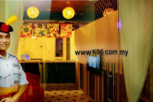 un hombre parado frente a una cocina con TV en Langit Langi Hotel @ KLIA/KLIA2, en Kampung Dengkil