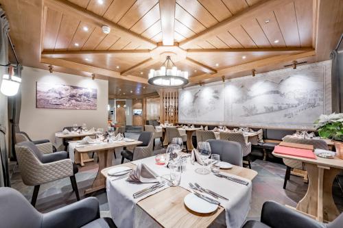 a restaurant with wooden ceilings and tables and chairs at Hotel Post Sils Maria in Sils Maria